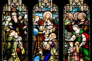 Stained glass window of parents bringing children to Jesus